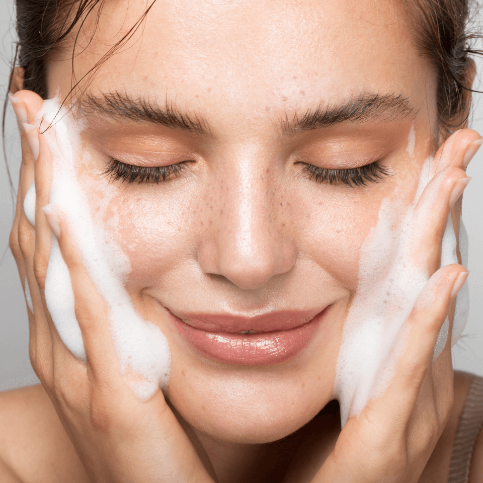 Cleansing Foam – lächelnde Frau reinigt ihr Gesicht mit Schaum