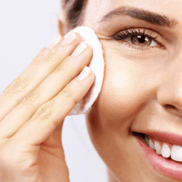 Hydrating Toner – Frau tupft Gesichtswasser mit Wattepad auf die Wange